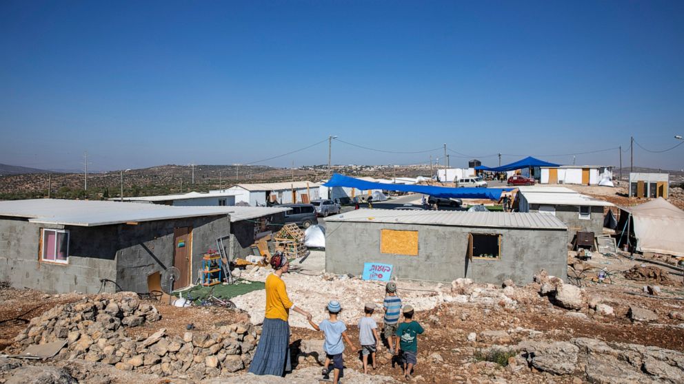 Israeli settlers walk at the recently established wildcat Jewish outpost of Eviatar, near the northern Palestinian West Bank town of Nablus, Monday, June 28, 2021. Palestinians say the outpost was established on private farmland. Israeli media said M