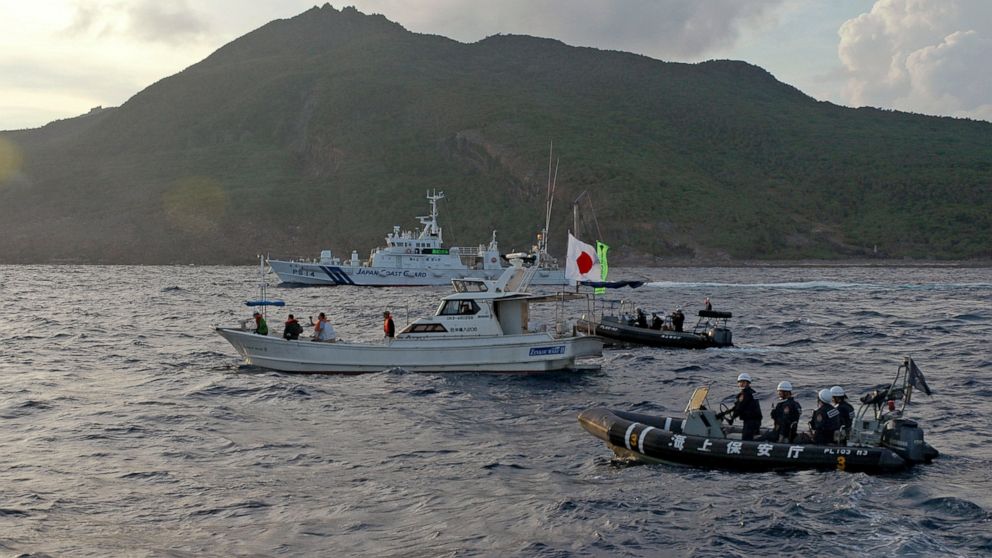 FILE - Japanese Coast Guard vessel and boats, rear and right, sail alongside a Japanese activists' fishing boat, center with a flag, near a group of disputed islands called Diaoyu by China and Senkaku by Japan, early Sunday, Aug. 18, 2013. Japan prot