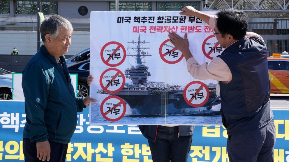 Protesters put stickers on a banner during a rally to oppose the planned the joint military exercises between the U.S. and South Korea in front of the U.S. Embassy in Seoul, South Korea, Thursday, Sept. 22, 2022. The nuclear-powered aircraft carrier 