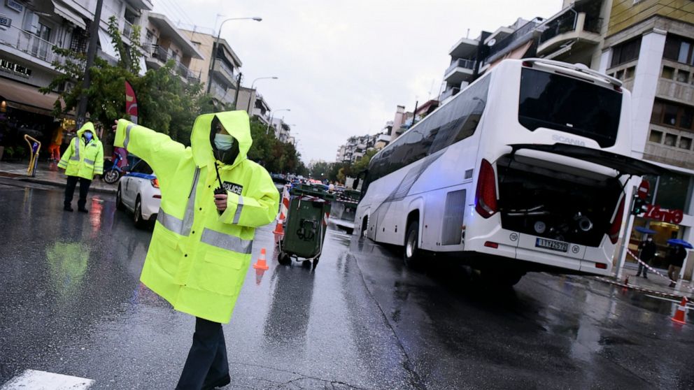Police cordon off a road after a bus transporting oil refinery workers fell into a sink hole in the northern city of Thessaloniki, Greece, Friday, Oct. 15, 2021. Storms continued to batter Greek cities, causing road closures and extensive flooding. (