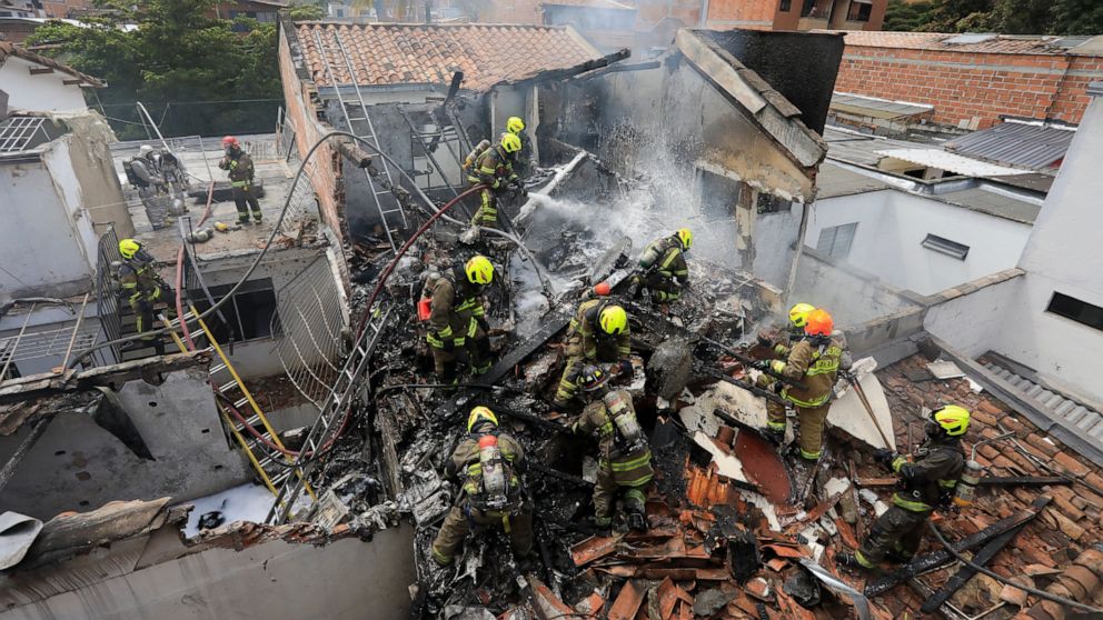 Firefighters work at the crash site of a small plane that fell on top of homes in a residential area of Medellin, Colombia, Monday, Nov. 21, 2022. The plane crashed shortly after taking off from Medellin's Olaya Herrera airport killing at least eight