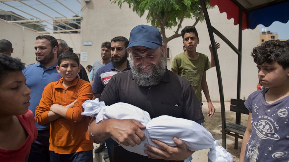 A man cries as he carries the body of a four-month-old Palestinian girl Maria Al-Ghazali, who was killed along with her parents in a late Sunday night Israeli missile strike on their family home, during her funeral in town of Beit Lahiya, northern Ga