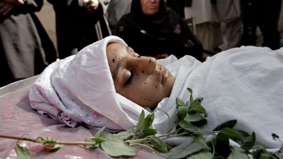 FILE - In this Oct. 27, 2013 file photo, relatives surround the body of a 10-year-old Afghan girl who was killed by a roadside bomb, apparently targeting a group of soldiers, during her funeral on the outskirts of Kabul, Afghanistan. America’s longes
