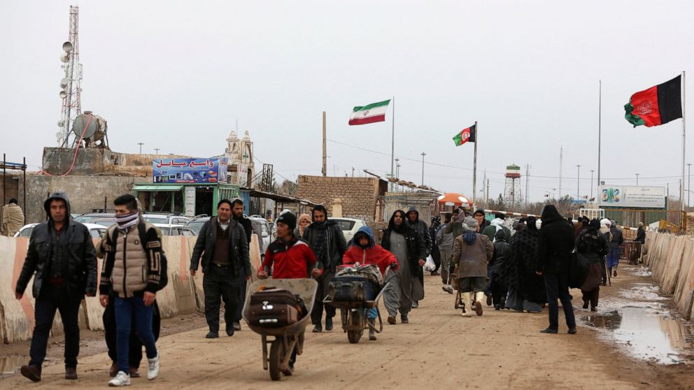 FILE- In this Feb. 20, 2019 file photo, Afghans return to Afghanistan at the Islam Qala border with Iran, in the western Herat Province. Taliban have taken control of Islam Qala crossing border in western Herat province at the neighboring Iran, an Af