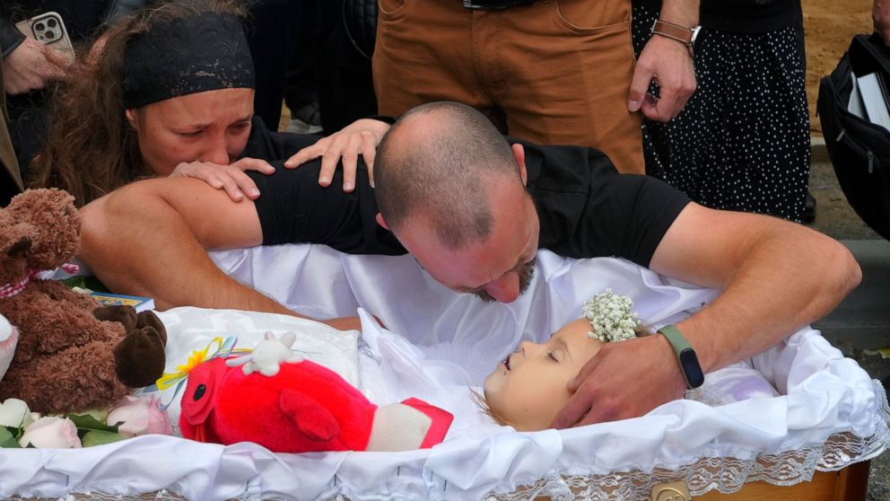 Artem Dmitriev gives the last salute to his daughter Liza, 4-year-old girl killed by Russian attack, in Vinnytsia, Ukraine, Sunday, July 17, 2022. Wearing a blue denim jacket with flowers, Liza was among 23 people killed, including two boys aged 7 an