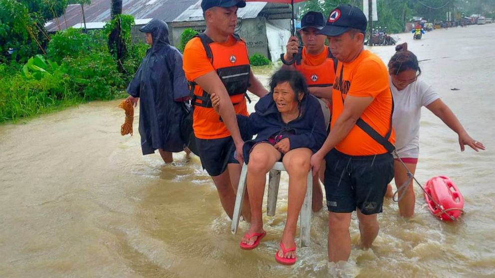 In this photo provided by the Philippine Coast Guard, rescuers evacuate residents from flood waters caused by Tropical Storm Nalgae in Hilongos, Leyte province, Philippines on Friday Oct. 28, 2022. Flash floods and landslides set off by torrential ra