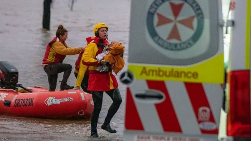 In this photo provided by the State Emergency Service, surf lifesaver Lee Archer carries a baby as the child and the mother are rescued from flood waters in Bulga, Australia, Wednesday, July, 6, 2022. Floodwaters were receding in Sydney and its surro