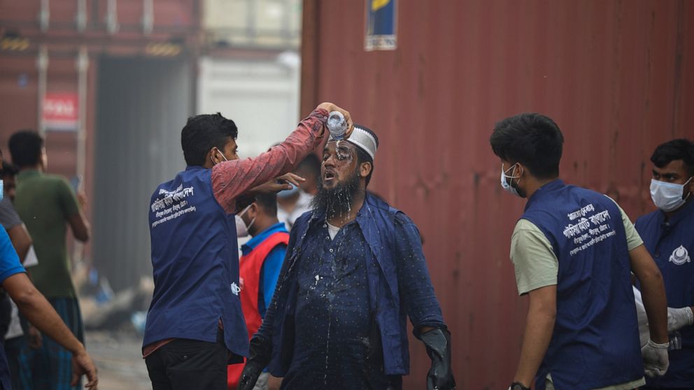A rescuer pours water on the face of another after a fire broke out at the BM Inland Container Depot, a Dutch-Bangladesh joint venture, in Chittagong, 216 kilometers (134 miles) southeast of capital, Dhaka, Bangladesh, early Sunday, June 5, 2022. Doz