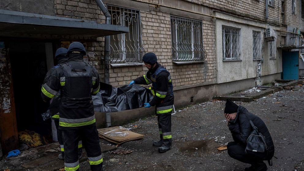 Lilia Kristenko, 38, cries as city responders collect the dead body of her mother Natalia Kristenko in Kherson, southern Ukraine, Friday, Nov. 25, 2022. Natalia Kristenko's dead body lay covered in a blanket in the doorway of her apartment building f