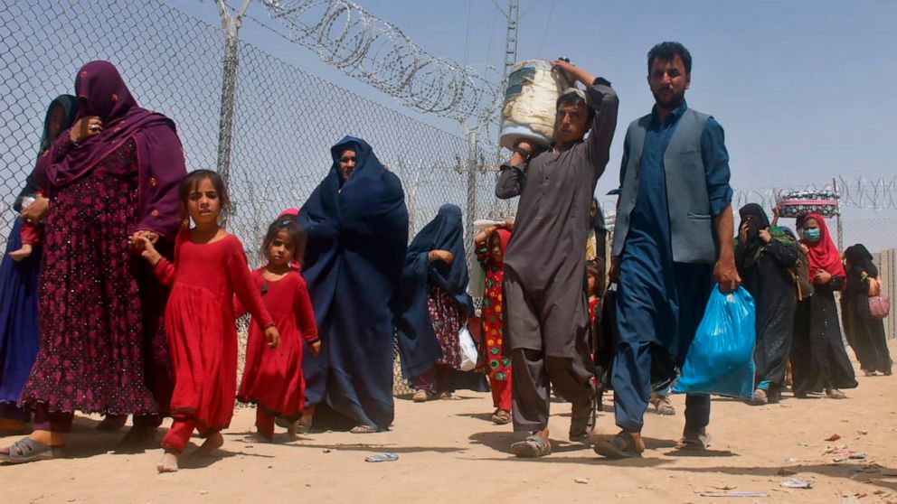 Afghans walk through a security barrier as they enter Pakistan through a common border crossing point in Chaman, Pakistan, Friday, Aug. 27, 2021. Hundreds of Pakistanis and Afghans cross the border daily through Chaman to visit relatives, receive med