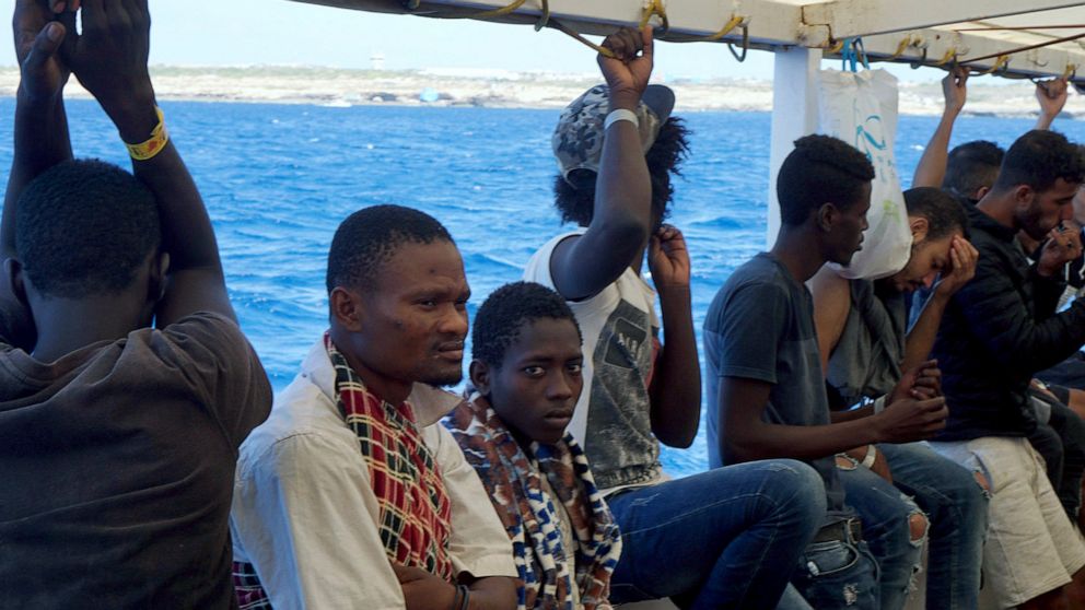 Migrants stand aboard the Open Arms Spanish humanitarian boat as it arrives near Lampedusa coast in the Mediterranean Sea, Thursday, Aug.15, 2019. A Spanish aid boat with 147 rescued migrants aboard is anchored off a southern Italian island as Italy'