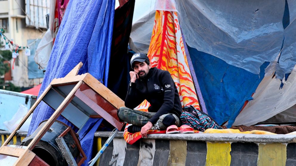 In this Saturday, March 7, 2020 photo, a protester sits outside his tent, in Baghdad, Iraq. The youth protesters are struggling to keep their movement going after one set-back after another, now capped by fears over the coronavirus outbreak. For most