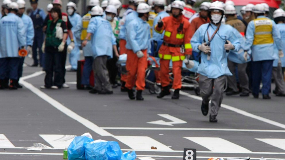 FILE - Shoes of victims are left on a street as rescuers from the Tokyo Metropolitan Police Department work in Tokyo's Akihabara district after a man rammed a truck into a crowd of shoppers, jumped out and went on a stabbing spree in Tokyo's top elec