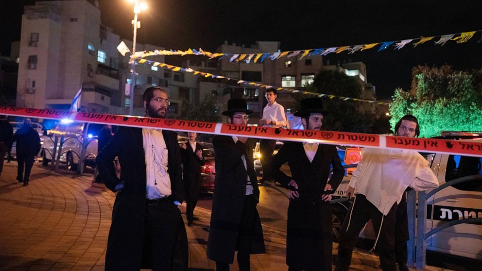 Ultra-Orthodox Jews stand behind police tape after a stabbing attack in the town of Elad, Israel, Thursday, May 5, 2022. Israeli medics say at least three people were killed in a stabbing attack near Tel Aviv on Thursday night. Israeli police said th