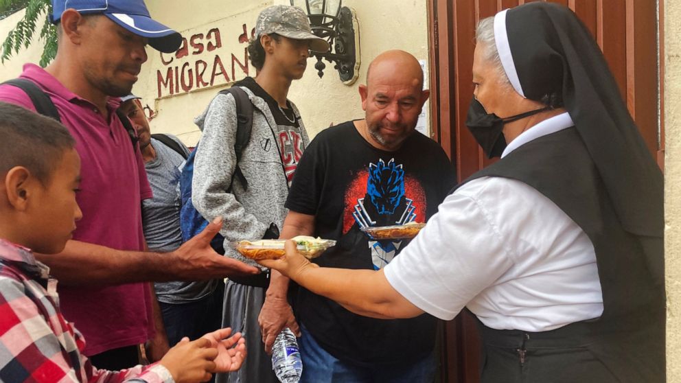 Isabel Turcios, director of the Casa del Migrante migrant services center delivers breakfasts of rice, beans and tortillas to migrants lined up outside, June 1, 2022 in Piedras Negras, Mexico. (AP Photo/Elliot Spagat)