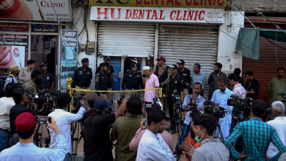 Police officers and media gather outside a dental clinic after a firing incident, in Karachi, Pakistan, Wednesday, Sept. 28, 2022. A gunman shot and killed a dual national Chinese-Pakistani man in an attack at a dental clinic in the southern port cit
