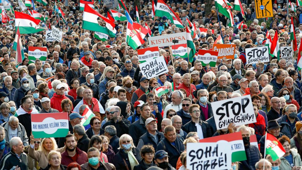 People hold banners that read "Never Again" during a march marking the 65th anniversary of the 1956 Hungarian revolution, in Budapest, Hungary, Saturday, Oct. 23, 2021. Thousands of supporters of Prime Minister Viktor Orban, who is expected to delive