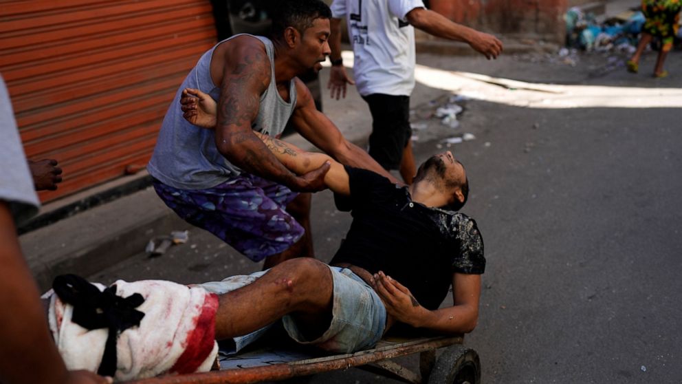 Residents place a wounded man on a dolly after a police operation that resulted in multiple deaths, in the Complexo do Alemao favela in Rio de Janeiro, Brazil, Thursday, July 21, 2022. Police said in a statement it was targeting a criminal group in R