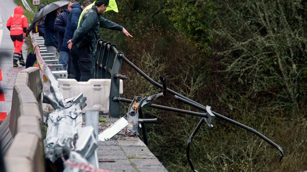 A civil guard points toward a bus after it plunged into a river near Pontevedra in northwestern Spain, Sunday, Dec. 25, 2022. Authorities say rescuers have recovered the victims from the bus that ran off a bridge and plunged into the river on Christm