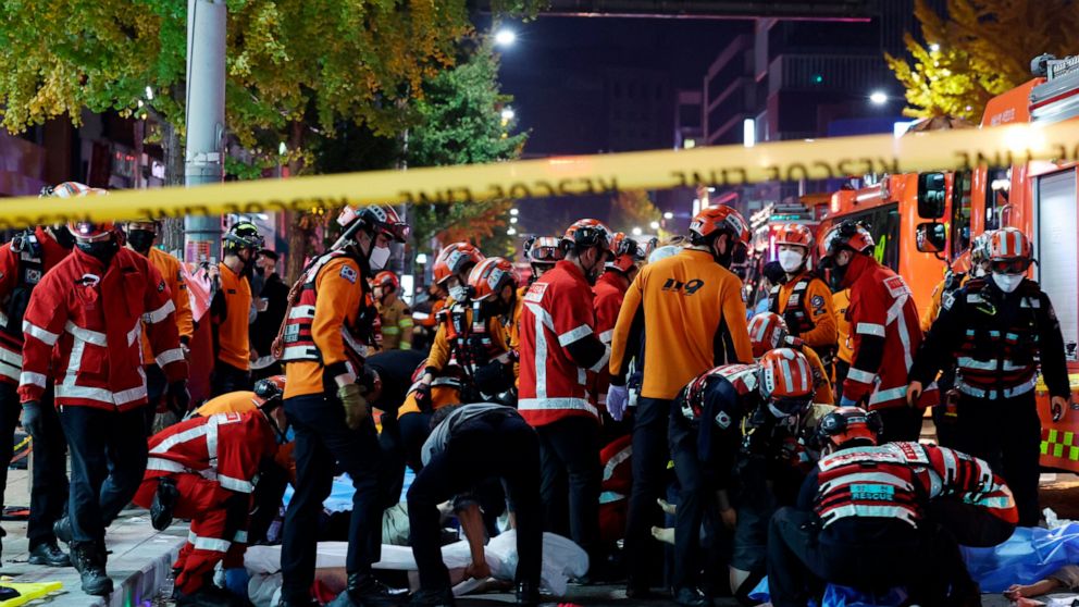 Rescue workers and firefighters work on the scene of a crushing accident in Seoul, South Korea, Saturday, Oct. 29, 2022. South Korean officials say dozens of people were in cardiac arrest after being crushed by a large crowd pushing forward on a narr