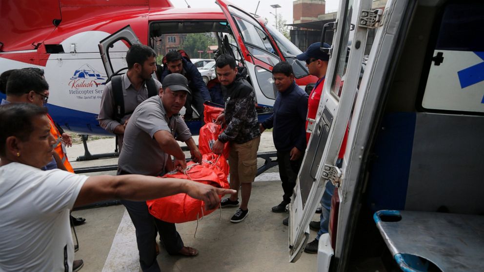 Hospital officials unload the dead body of a plane crash victim outside the Teaching Hospital in Kathmandu, Nepal, Sunday, April 14, 2019. At least three people were killed and four injured on Sunday after a small plane crashed into a parked helicopt