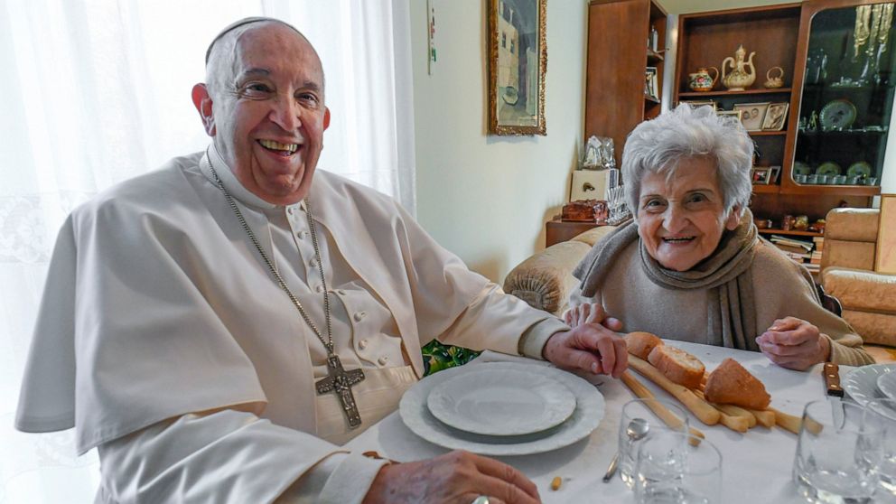 In this image made available by Vatican Media, Pope Francis sits for lunch in the home of a cousin, Carla Rabezzana, right, in the town of Portacomaro, about 10 kilometers (six miles) east of Asti, northern Italy, Saturday, Nov. 19, 2022. Rabezzana t