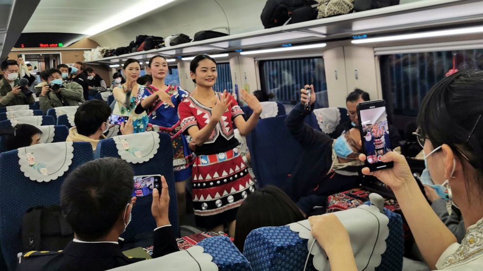 Women in ethnic dresses perform on a passenger carriage of the first regular train service on the Chinese section of the railway between Kunming and Vientiane, the Laotian capital, after its debut ceremony in Kunming in southwestern China's Yunnan pr