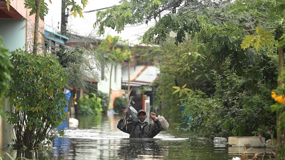 A resident wades through floodwaters, Thursday, Sept. 29, 2022, in Ubon Ratchathani province, northeastern Thailand. Heavy rains and strong winds from tropical storm Noru swept across parts of northeastern Thailand on Thursday morning, knocking down 