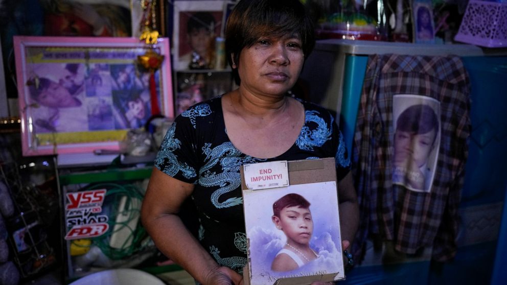 Emily Soriano holds a picture of her 15-year-old son as she recounts how he was gunned down with four friends and two other residents while partying in a Philippine slum six years ago during an interview with the Associated Press at their home in Man