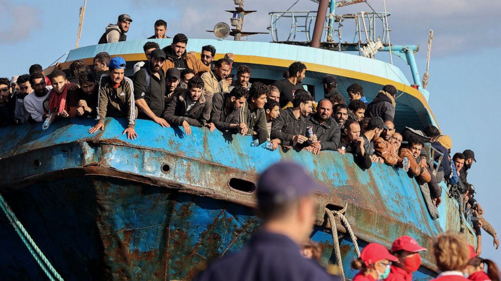 Migrants look out of a fishing boat docked at the port of Palaiochora in southeastern Crete, Greece, after its arrival, on Tuesday, Nov. 22, 2022 . Greek authorities say a fishing boat crammed with hundreds of migrants that lost steering and had been
