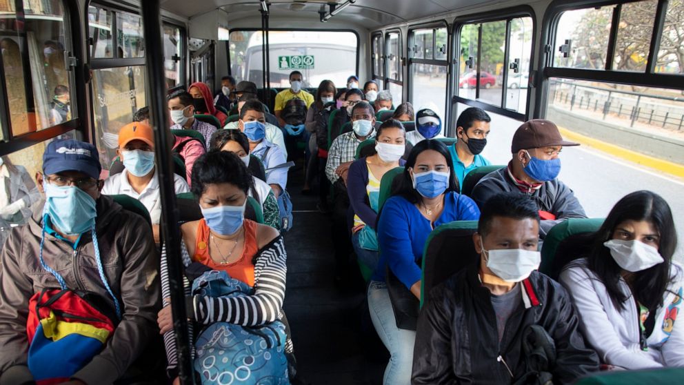 People wearing protective masks as a precaution against the spread of the new coronavirus travel on a bus in Caracas, Venezuela, Tuesday, March 17, 2020. President Nicolas Maduro ordered citizens to stay home, and to wear a mask in public under a qua