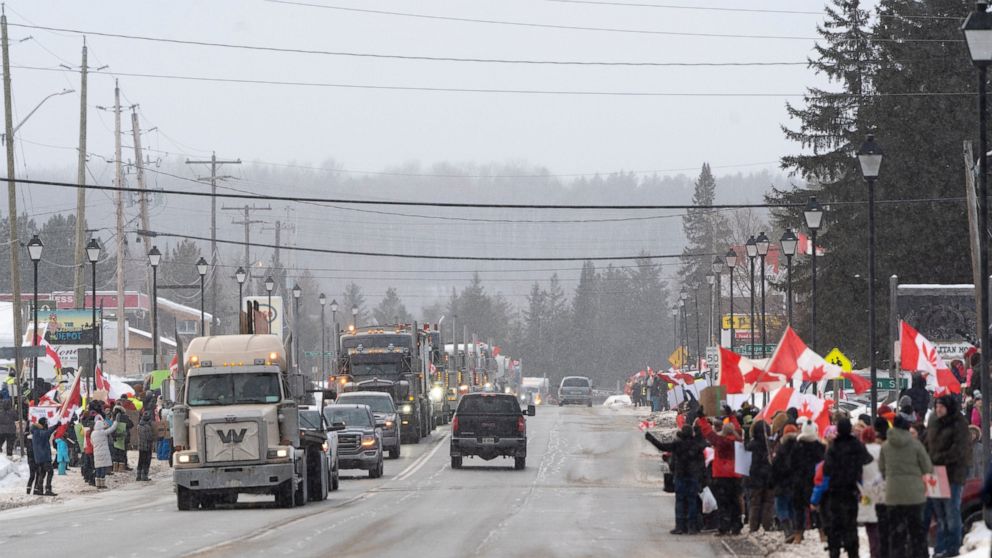 Protesters and supporters against a COVID-19 vaccine mandate for cross-border truckers cheer as a parade of trucks and vehicles pass through Kakabeka Falls outside of Thunder Bay, Ontario, on Wednesday, Jan. 26, 2022. (David Jackson/The Canadian Pres