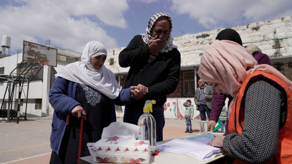 Palestinians look for their polling station to cast their votes in the municipal elections at the West Bank town of Beit Furik, Saturday, March 26, 2022. (AP Photo/Majdi Mohammed)