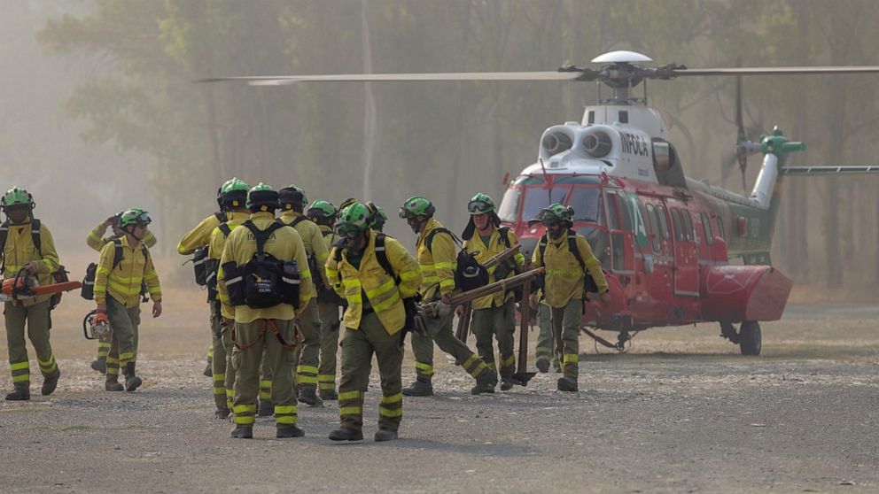 Firefigters walk in the area of a wildfire in Pujerra, Malaga, on Thursday, June 9, 2022. Emergency services deployed almost 1,000 firefighters, military personnel and support crews Thursday to fight a wildfire that has forced the evacuation of some 