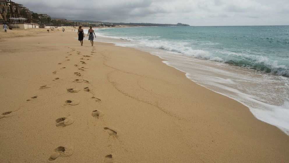 FILE - Tourists walk on the beach in Cabo San Lucas, in Mexico's western Baja California Peninsula, Sept. 2, 2009. The U.S. government warned Americans on Jan. 26, 2022 to avoid a hospital at this beach destination following years of complaints that 