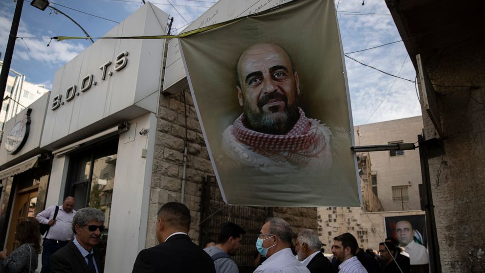 FILE - Family members receive condolences under a poster with a picture of Palestinian Authority outspoken critic Nizar Banat, during his memorial service, in the West Bank city of Ramallah, Saturday, Oct. 16, 2021. Amnesty International said Friday,