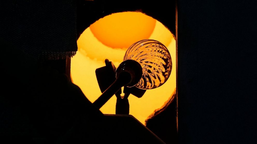 A glass-worker heats a glass artistic creation in a methane powered oven in Murano island, Venice, Italy, Thursday, Oct. 7, 2021. The glassblowers of Murano have survived plagues and pandemics and have transitioned to highly prized artistic creations