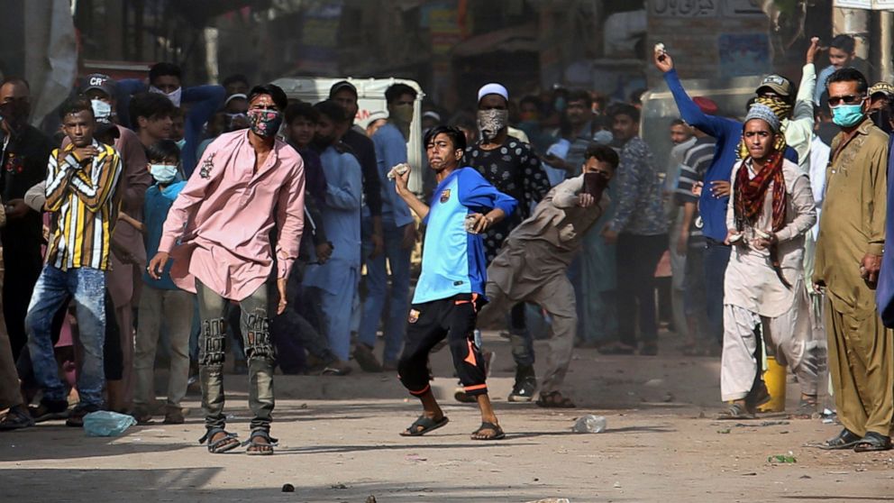 Supporters of Tehreek-e-Labiak Pakistan, a banned Islamist party, throw stones after police fire tear gas to disperse protests over the arrest of their party leader Saad Rizvi, in Karachi, Pakistan, Monday, April 19, 2021. The outlawed Islamist polit