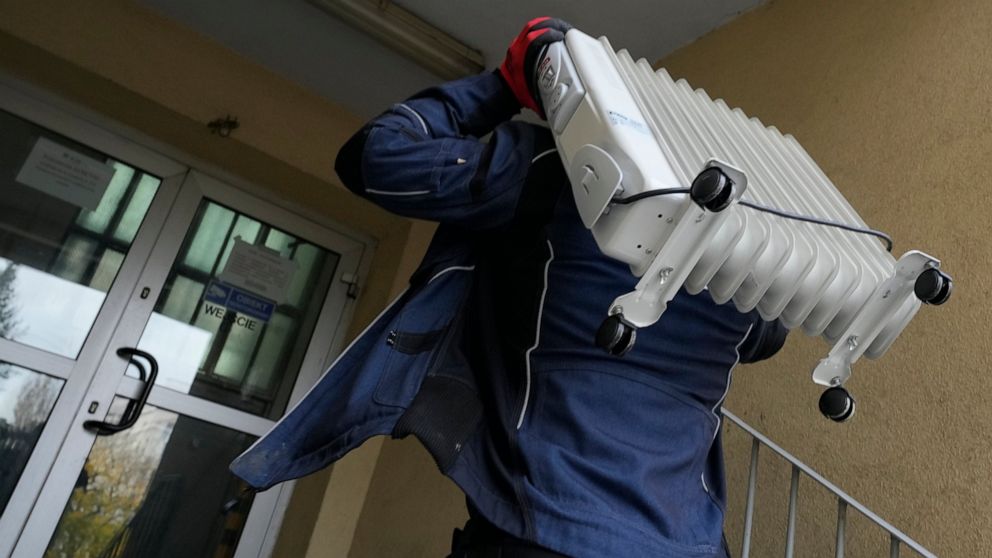A man carries a heater into an apartment building in Warsaw, Poland, Oct. 27, 2021. Gas prices are soaring, leading some people to turn down their radiators and only heat individual rooms. Poland's central bank made its second interest rate hike in a
