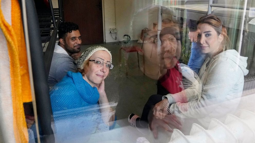 Boshra al-Moallem, bottom left, looks out of the window as she sits in a room with her two sisters and brother-in-law at a refugee center in Bialystok, Poland, on Wednesday, Sept. 29, 2021. After enduring a decade of war in Syria, Boshra al-Moallem a