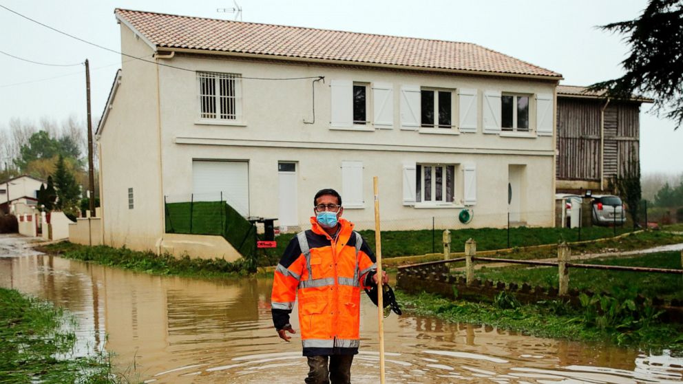 A volunteer walks through water on a flooded road in Coussan, near Marmande southwestern France, Saturday, Feb. 6, 2021. Rivers across France broke their banks this week amid heavy flooding. In southern France, waters are starting to recede after the