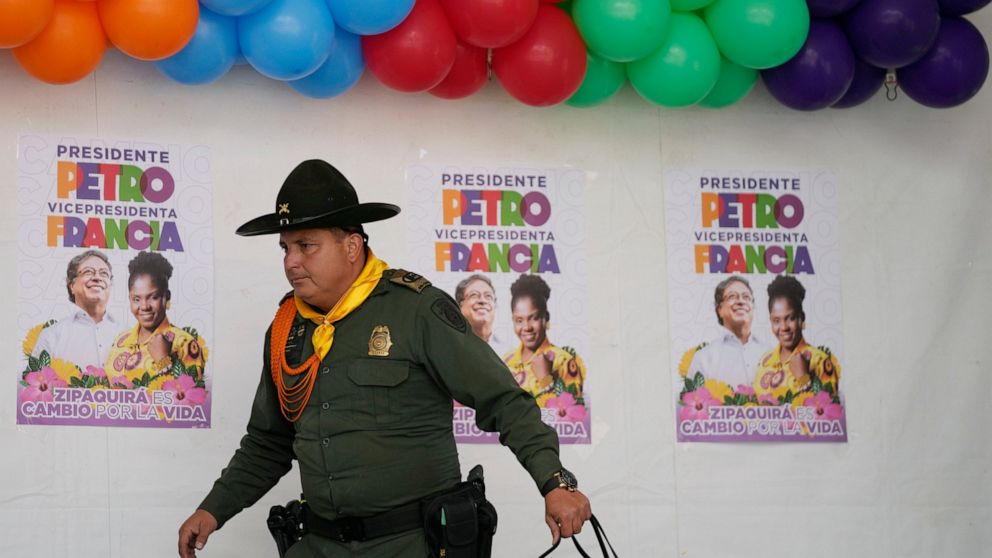 A police officer walks past posters of Historical Pact coalition presidential candidate Gustavo Petro and his running mate Francia Marquez during a closing campaign rally in Zipaquira, Colombia, Sunday, May 22, 2022. Elections are set for May 29. (AP