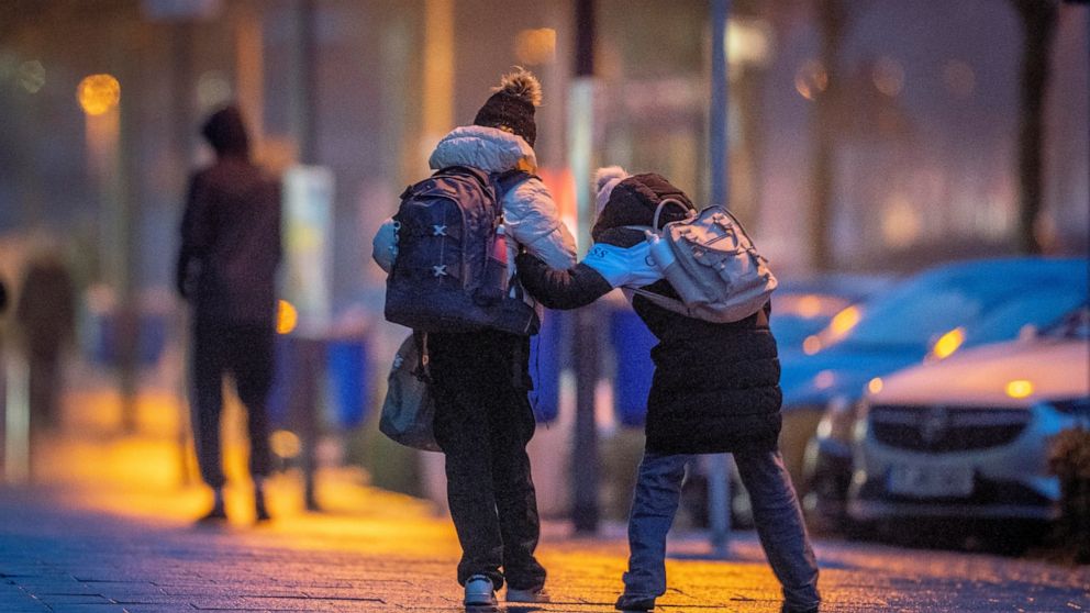 School children help each other on the way to school in icy conditions when rain fell on a frosted surface in Frankfurt, Germany, early Monday, Dec. 19, 2022. (AP Photo/Michael Probst)