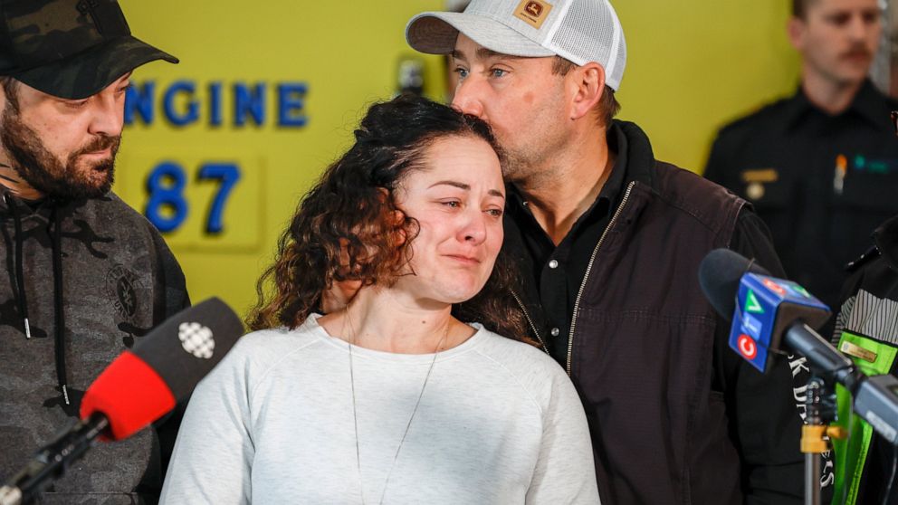 Paramedic Jayme Erickson, center, who was called to a crash last week and didn't know she was trying to save her own daughter because the injuries were too severe, is comforted by her husband Sean Erickson, as she speaks to the media in Airdrie, Albe