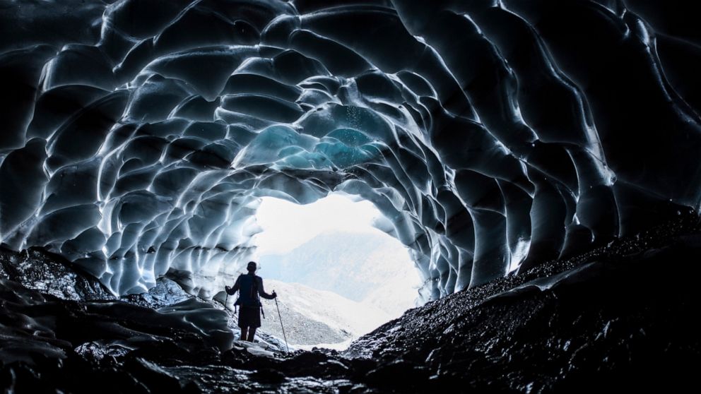 FILE - A man stands in a glacier cave at the Sardona glacier, July 27, 2022, in Vaettis, Switzerland. The melting glacier has revealed a cave. Faced with increasing demand for alpine water resources at a time of accelerating glacier melt, policymaker