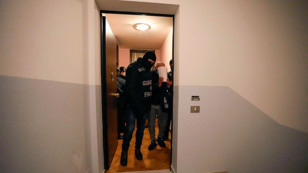 Iraqi suspect Alaa Qasim Rahima is escorted by Italian Finance Police, after his arrest along with his brother, in Fossalta di Piave, northern Italy, Wednesday, Jan. 19, 2022. Police in Italy and Albania arrested more than 20 people accused of cashin