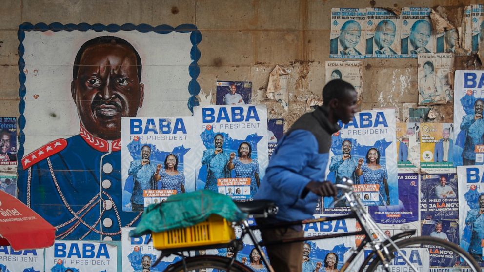 A man pushes a bicycle past campaign posters for Kenyan presidential candidate Raila Odinga, referred to affectionately as "Baba", the Swahili word for "father", and his running mate Martha Karua, in the low-income Kibera neighborhood of Nairobi, Ken