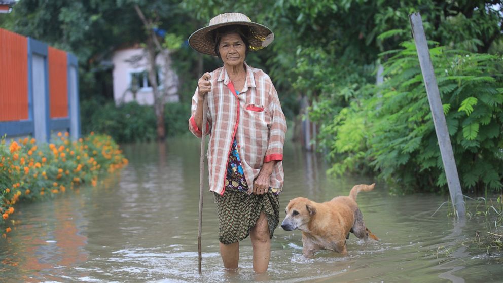 A woman wades through floodwaters in Nakhon Rachasima province, northeastern of Bangkok, Thailand, Monday, Oct. 18, 2021. Heavy rains in central and northeastern Thailand have caused fresh flooding, causing authorities to release water into one alrea