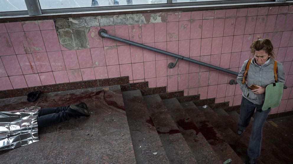 A woman walks next to the body of a man killed during shelling in Kharkiv, eastern Ukraine, Thursday, May 26, 2022. (AP Photo/Bernat Armangue)