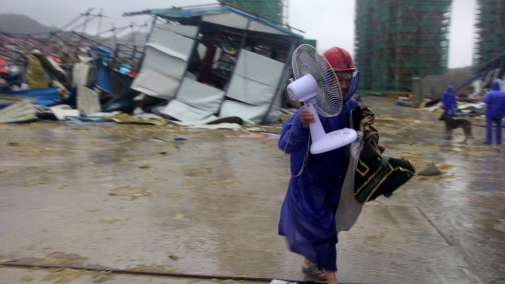 A worker removes an electric fan from a temporary dormitory that collapse as Typhoon Lekima sweeps through Wenling in eastern China's Zhejiang province Saturday, Aug. 10, 2019. China issued its top warning for coastal areas of Zhejiang province Frida